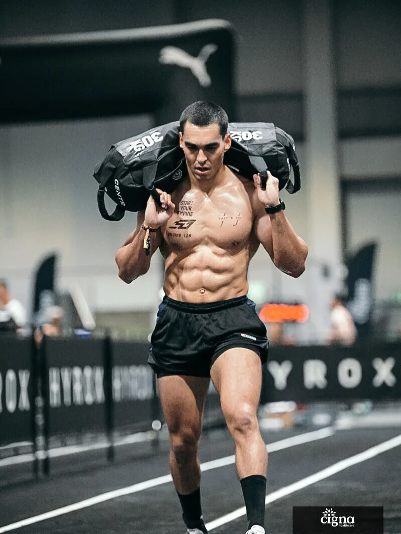 Athlete carrying a weighted bag across his shoulders during a fitness race