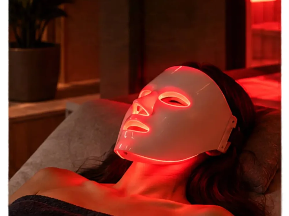 Client relaxing with a red LED face mask at Fast & Fit