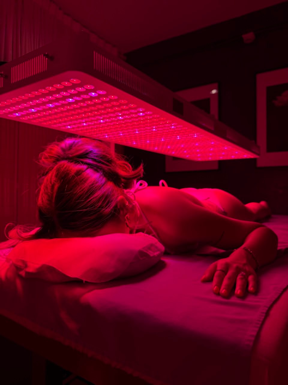 ผู้หญิงนอนคว่ำระหว่างการบำบัดด้วย Red Light Therapy